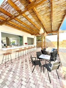 een patio met stoelen en tafels en een bar bij Mediterranea Apartments in Kato Daratso