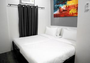 a bedroom with a white bed and a black curtain at mySTAY Hotel BGC South in Manila