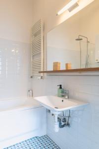 a white bathroom with a sink and a tub at Bright & Spacious Loft With Basilica View in Budapest
