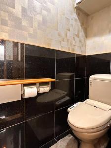 a bathroom with a white toilet and black tiles at COZY ROOM 三丁目〜難波日本橋駅奈良駅直通/6人まで/商店街近く～60㎡快適空間～ in Osaka