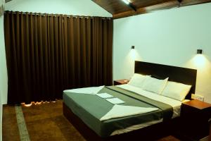 1 dormitorio con 1 cama con cortinas negras en The Nest Thattekad, en Thattakād