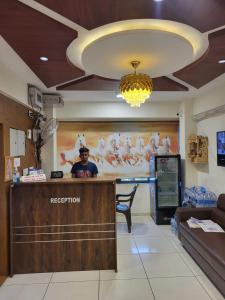 a man standing at a reception desk in a room at Hotel Shreeji's in Gandhinagar