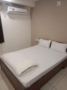 a bed with white sheets and pillows in a room at Hotel Shreeji's in Gandhinagar