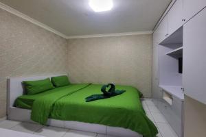 a bedroom with a green bed with a black swan statue at B Nature Aeropolis Inn in Teko