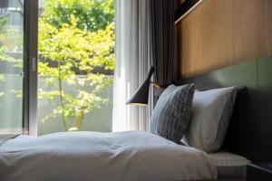 Schlafzimmer mit einem Bett, einem Fenster und einer Lampe in der Unterkunft Hotel Liberte Kyoto Gojo in Kyoto