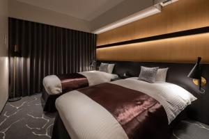 ein Hotelzimmer mit 2 Betten und einer Wand in der Unterkunft Hotel Liberte Kyoto Gojo in Kyoto