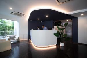 Due persone in piedi dietro un bancone bianco in una hall di Harbour Ville Hotel a Singapore