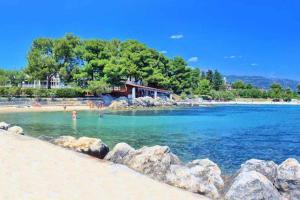 a beach with people in the water and rocks at Apartment Bella Costa II. in Kaštela