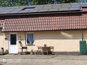 a house with a table and chairs and a solar roof at La bergerie in La Bruyère