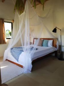 a bedroom with a bed with a mosquito net at Tropical Bungalows-Siargao in General Luna