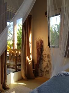 een slaapkamer met een bed met gordijnen en een raam bij Prana Siargao Resort in General Luna