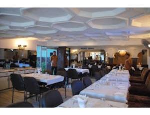 uma sala de jantar com mesas e cadeiras brancas em Hotel Sukhakarta, Nagpur em Nagpur