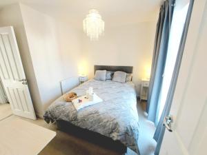 a bedroom with a bed and a chandelier at 3-BED HOUSE, FULL KITCHEN, ENSUITE, SMART TV in all rooms, KETLEY, TELFORD in Telford