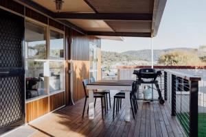 a deck with a table and chairs and a grill at Cedar House ~ Family Fun! in Bicheno
