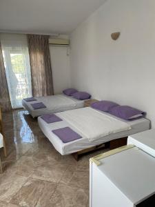 drie bedden in een kamer met paarse kussens bij Apartments Neda in Sutomore