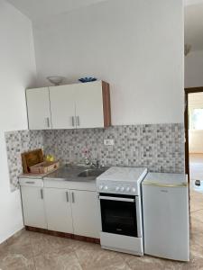 een keuken met witte kasten en een fornuis met oven bij Apartments Neda in Sutomore