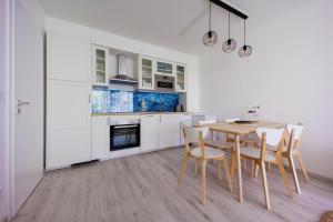a kitchen with white cabinets and a table and chairs at White&Blue Apartman in Siófok