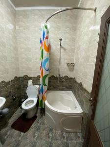 uma casa de banho com um WC e uma cortina de chuveiro em Davan LUX em Tashkent