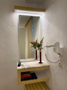 a bathroom with a mirror and a vase with flowers on a shelf at Olympic Kosma Hotel & Villas - Hanioti in Hanioti