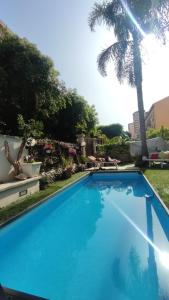 una piscina blu in un cortile con una palma di Casa Le Rose a Palermo