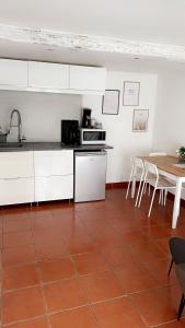 a kitchen with white cabinets and a table with chairs at La lavande in Arles