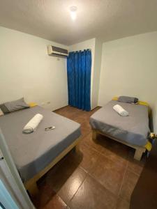 - 2 lits dans une chambre dotée de rideaux bleus dans l'établissement Casa Gn 37 Excellent Location North of the city Guaymas Sonora, à Guaymas