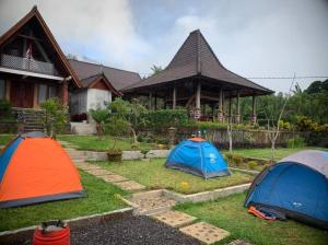 three tents in the grass in front of a house at Villa Pondok Dauh Saba in Tabanan