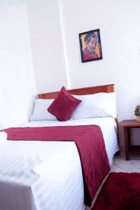 - une chambre avec 2 lits dotés de draps blancs et rouges dans l'établissement Bamburi 2BR Apartment, à Mombasa