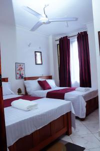 Cette chambre d'hôtel comprend 2 lits avec des rideaux rouges. dans l'établissement Bamburi 2BR Apartment, à Mombasa