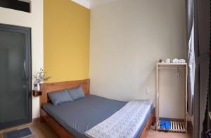 1 dormitorio con 1 cama en una habitación con paredes amarillas en TRI'S Homestay, en Quy Nhon