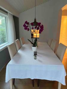 a white table with a vase of flowers on it at Trevligt hus med vacker omgivning in Stockholm