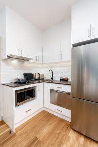 a kitchen with white cabinets and a stainless steel refrigerator at Hunter Studios - Maitland in Maitland