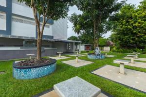 a park with benches and a tree in front of a building at Hotel Merlin International in Trichūr