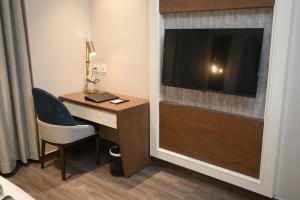 a hotel room with a desk with a television and a chair at Hotel Apricia in Ludhiana +20 photos