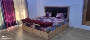 a bed with a wooden frame in a room at Noor Guest House in Leh