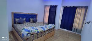 a bedroom with a bed with blue walls and blue curtains at Noor Guest House in Leh