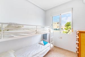 sypialnia z dwoma łóżkami piętrowymi i oknem w obiekcie Playa Flamenca Townhouse w mieście Orihuela +16 zdjęć