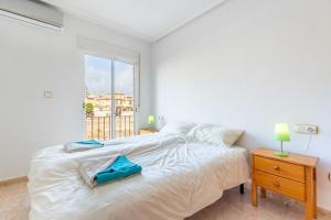 biała sypialnia z dużym łóżkiem i oknem w obiekcie Playa Flamenca Townhouse w mieście Orihuela