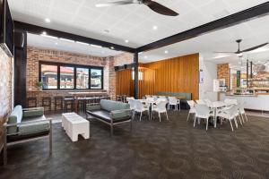 a dining room with tables and white chairs at Pier Hotel Coffs Harbour in Coffs Harbour