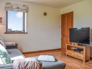 a living room with a couch and a flat screen tv at Failte in Gamrie