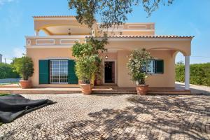 a house with potted trees in front of it at Casa do Sobreiro in Quelfes