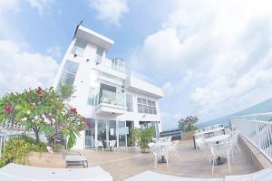 a white house with tables and chairs on a balcony at La Vogue Boutique Hotel & Casino in Sihanoukville