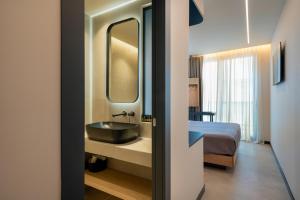 a bathroom with a sink and a bed and a mirror at Nema Hotel Athens in Athens