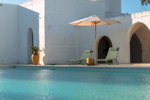 2 sillas y sombrilla junto a la piscina en Masseria Rescio en Avetrana