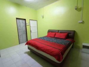 um quarto com uma cama com almofadas vermelhas e paredes verdes em Hajjah Homestay Tg Agas Muar em Muar