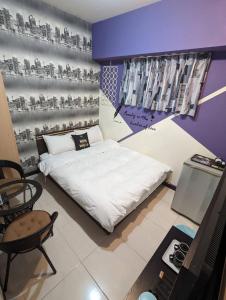 1 dormitorio con cama blanca y pared morada en 一中宿屋 en Taichung