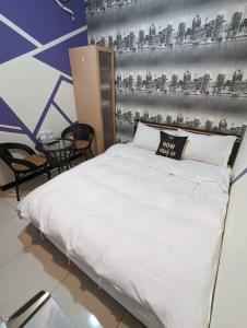 a white bed in a room with a wall at 一中宿屋 in Taichung