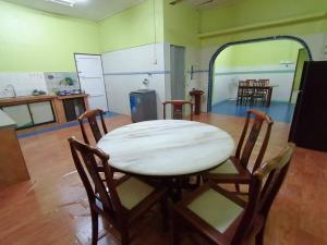 uma sala de jantar com uma mesa e cadeiras num quarto em Hajjah Homestay Tg Agas Muar em Muar