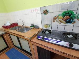a kitchen with a sink and a stove at Hajjah Homestay Tg Agas Muar in Muar