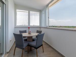 a dining room with a table and chairs and windows at Apartment Harmony in Umag